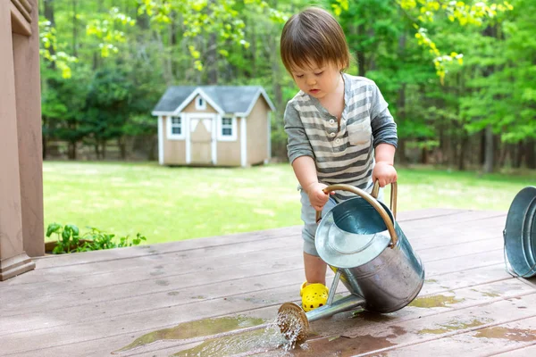 Toddler boy playing with a watering can — Stock Photo, Image