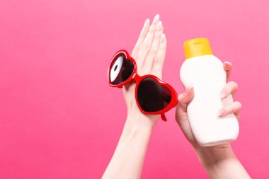Güneş kremi ve güneş gözlüğü şişe tutan el