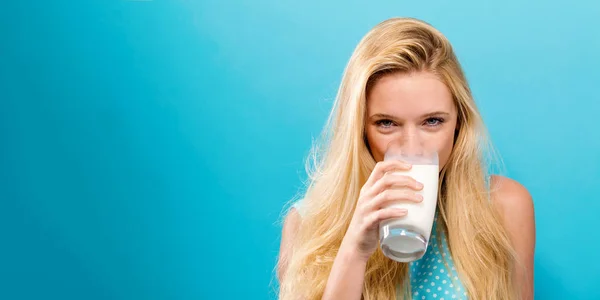 Glad ung kvinna dricka mjölk på en enfärgad bakgrund — Stockfoto