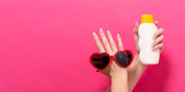 Güneş kremi ve güneş gözlüğü şişe tutan el