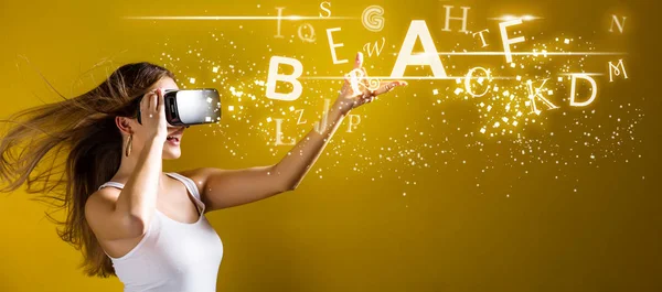 Alfabetos com mulher usando um fone de ouvido de realidade virtual — Fotografia de Stock