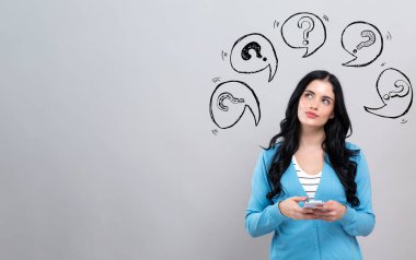 Konuşma baloncuklarıyla soru işaretleri, elinde akıllı telefon tutan bir kadın.