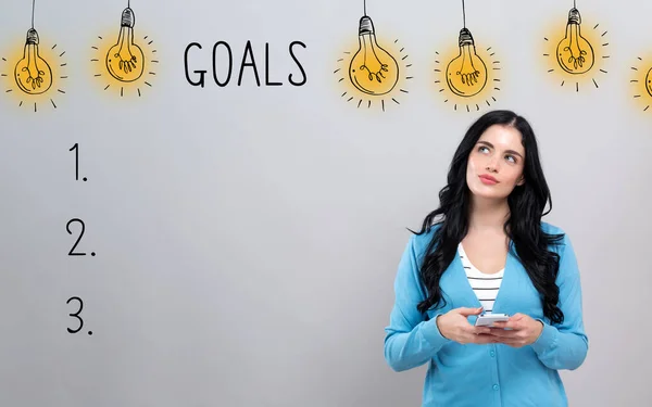 Goal list with woman holding a smartphone — Stok fotoğraf