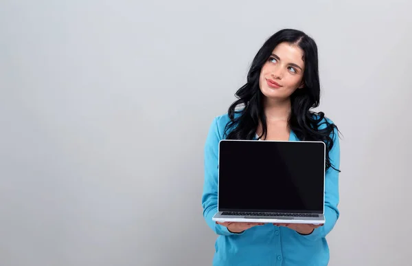 Молода жінка з портативним комп'ютером у вдумливій позі — стокове фото