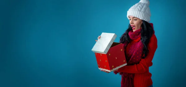 Mujer joven con sombrero de santa apertura de una caja de regalo de Navidad — Foto de Stock