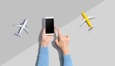 Elinde uçaklarla akıllı bir telefon tutan kişi.
