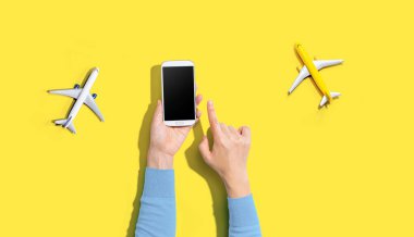 Elinde uçaklarla akıllı bir telefon tutan kişi.