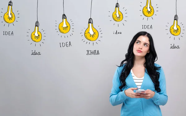 Idea light bulbs with woman holding a smartphone — 스톡 사진