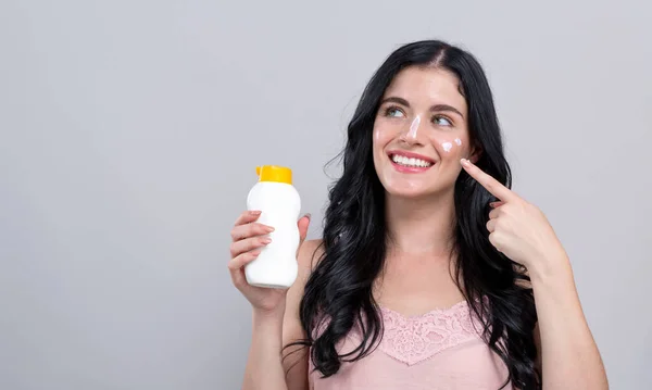 Jonge vrouw met zonnebrandcrème — Stockfoto