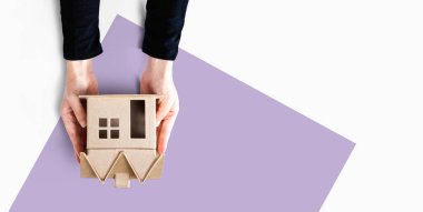 Elinde karton bir ev tutan kadın.