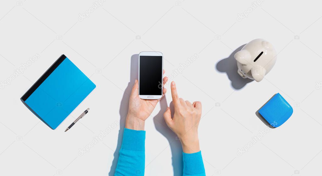 Person using smartphone with piggy bank