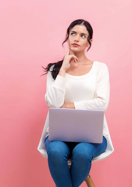 Jonge vrouw met een laptop in een doordachte pose — Stockfoto