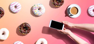 Akıllı telefon ve donut kullanan biri.