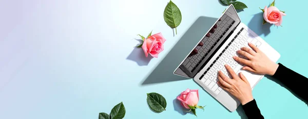 Woman using her laptop with pink roses