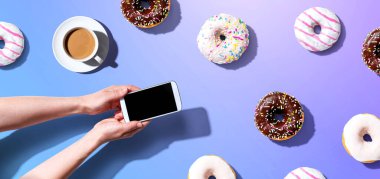 Akıllı telefon ve donut kullanan biri.