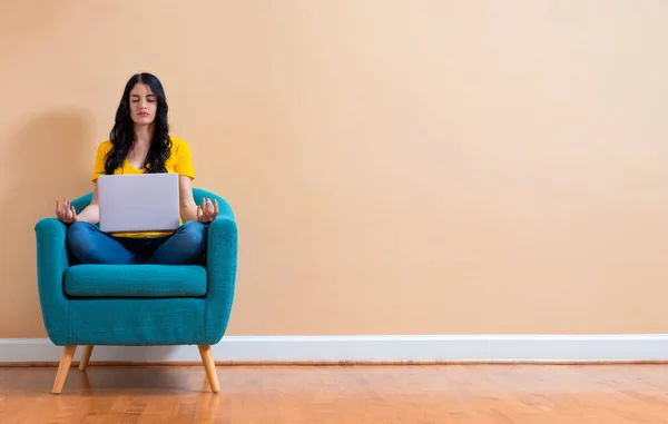 Jonge vrouw met laptop in een meditatie pose — Stockfoto