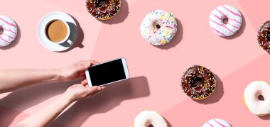 Akıllı telefon ve donut kullanan biri.