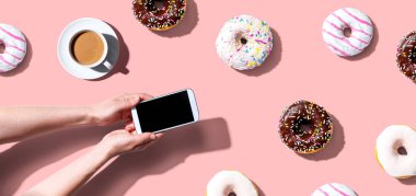 Akıllı telefon ve donut kullanan biri.