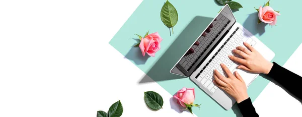 Woman using her laptop with pink roses