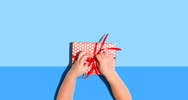 Küçük çocuk yukarıdan bir hediye kutusu yapıyor. — Stok fotoğraf