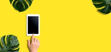 Tropikal yapraklı tablet bilgisayar kullanan kişi