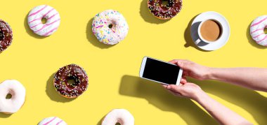 Akıllı telefon ve donut kullanan biri.