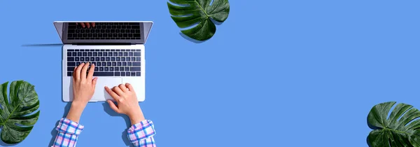 Personne utilisant un ordinateur portable avec des feuilles tropicales — Photo
