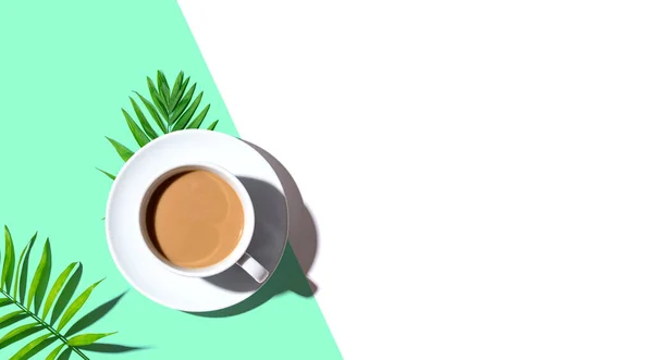 Une tasse de café aux feuilles tropicales — Photo