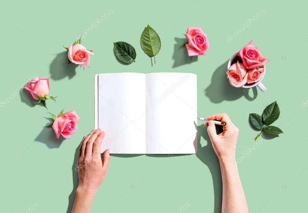 Woman writing in a notebook with pink roses