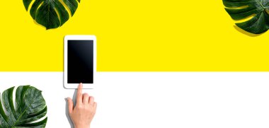Tropikal yapraklı tablet bilgisayar kullanan kişi
