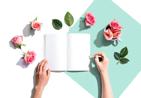 Жінка пише в блокноті з рожевими трояндами — стокове фото