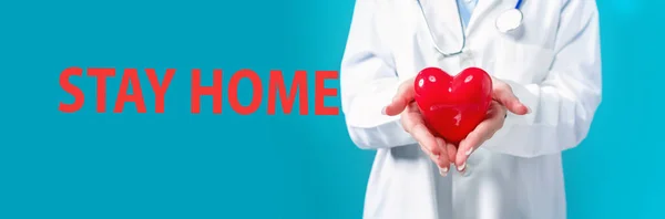 Bleiben Sie zu Hause Thema mit einem Arzt, der ein Herz hält — Stockfoto