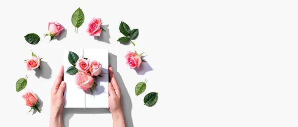 Mani femminili in possesso di una confezione regalo con rose rosa — Foto Stock