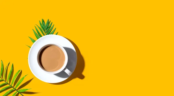 Une tasse de café aux feuilles tropicales — Photo