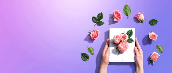 Manos femeninas sosteniendo una caja de regalo con rosas rosadas —  Fotos de Stock