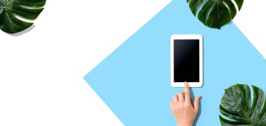 Tropikal yapraklı tablet bilgisayar kullanan kişi