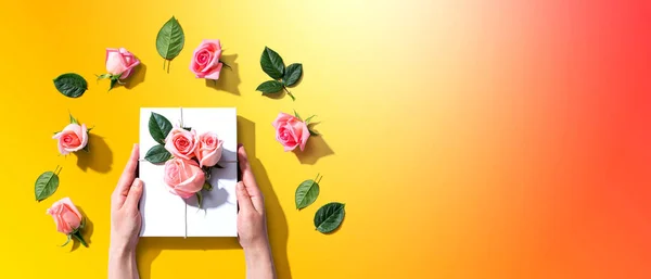 Manos femeninas sosteniendo una caja de regalo con rosas rosadas —  Fotos de Stock