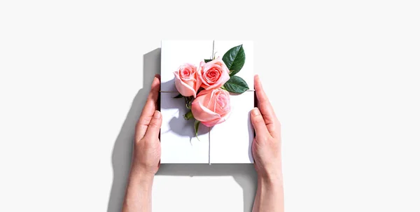 Manos femeninas sosteniendo una caja de regalo con rosas rosadas —  Fotos de Stock