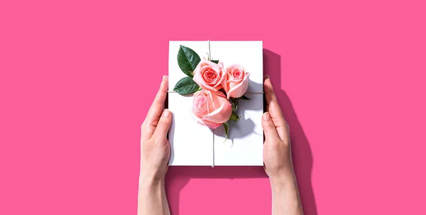 Vrouwelijke handen met een geschenkdoos met roze rozen — Stockfoto