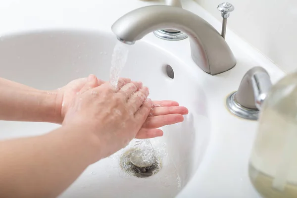 Persoon die zijn handen wast met water en zeep — Stockfoto