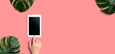 Tropikal yapraklı tablet bilgisayar kullanan kişi