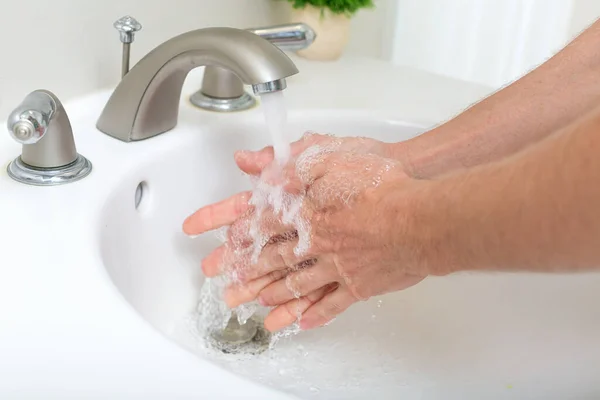 Persoon die zijn handen wast met water en zeep — Stockfoto