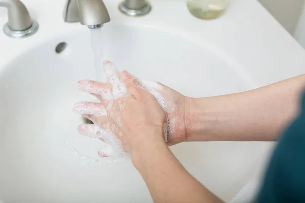 Persoon die zijn handen wast met water en zeep — Stockfoto