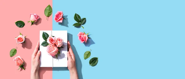 Manos femeninas sosteniendo una caja de regalo con rosas rosadas —  Fotos de Stock