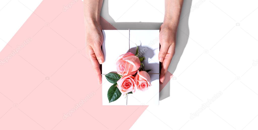 Female hands holding a gift box with pink roses