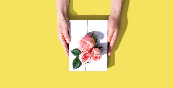 Vrouwelijke handen met een geschenkdoos met roze rozen — Stockfoto