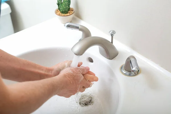 Persoon die zijn handen wast met water en zeep — Stockfoto