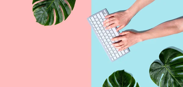 Osoba używająca klawiatury komputerowej z liśćmi tropikalnymi — Zdjęcie stockowe