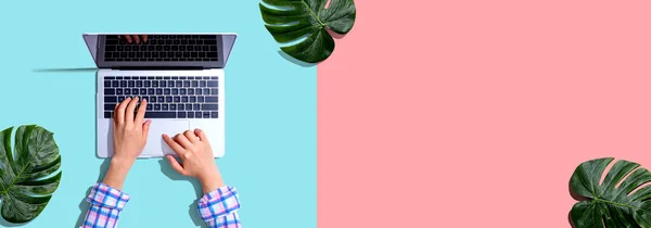 Persoon die een laptop met tropische bladeren gebruikt — Stockfoto