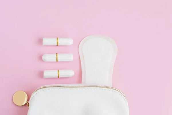 tampons and menstrual pads in a cosmetic bag on a pink background. woman period concept.